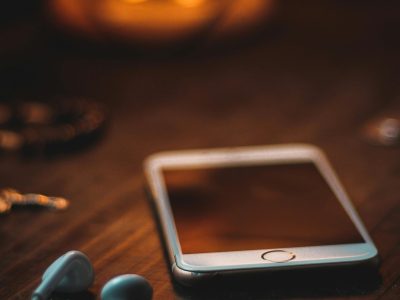 Mobile phone with earphones on a wooden table in warm ambient light, creating a cozy atmosphere.
