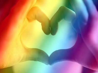 Hands forming a rainbow heart shape, symbolizing love, unity, and LGBTQ pride.