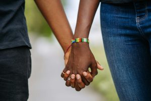 Close-up of two people holding hands, emphasizing connection and inclusivity.