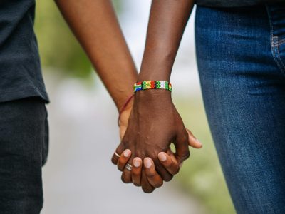 Close-up of two people holding hands, emphasizing connection and inclusivity.