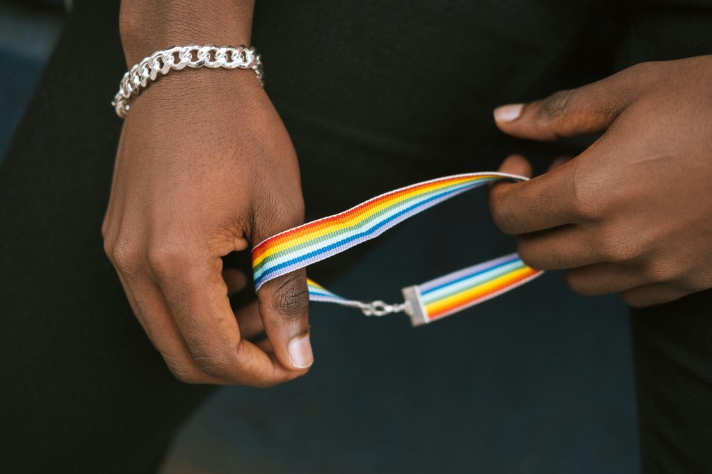 A person holds a rainbow wristband symbolizing LGBTQ+ pride and identity.