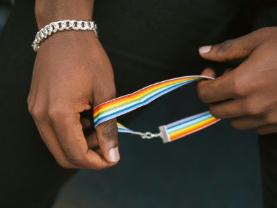 A person holds a rainbow wristband symbolizing LGBTQ+ pride and identity.